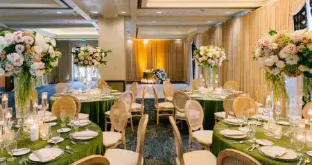 Reception room with dining tables topped with tall floral arrangements