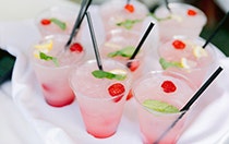 A tray with 8 cocktails garnished with raspberries, mint and lemon