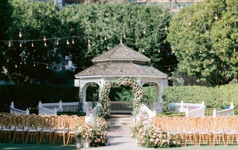 A grand gazebo flanked by curving walkways, floral decor and rows of chairs