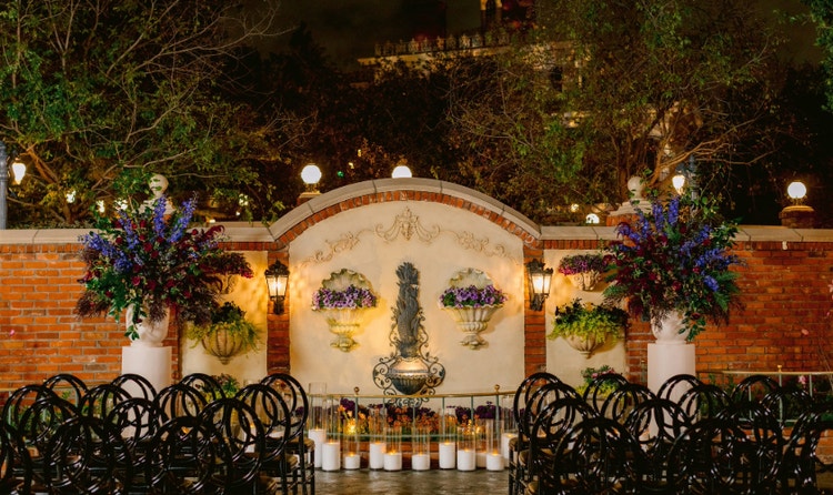 The Magnolia Park Terrace wedding venue with a fountain, floral arrangements, chairs and Haunted Mansion in the background