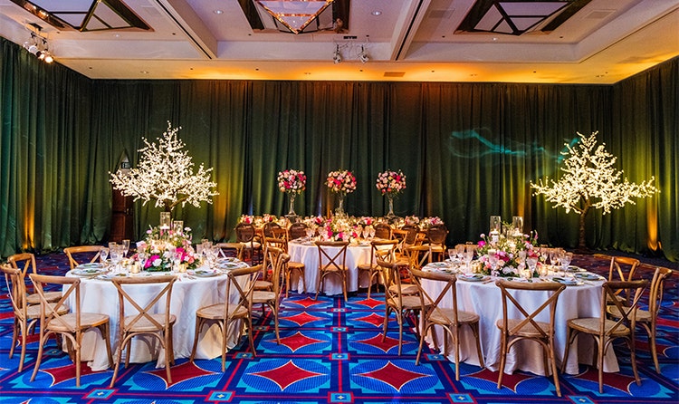 Three round tables with floral centerpieces and a rectangular table in the back of the room