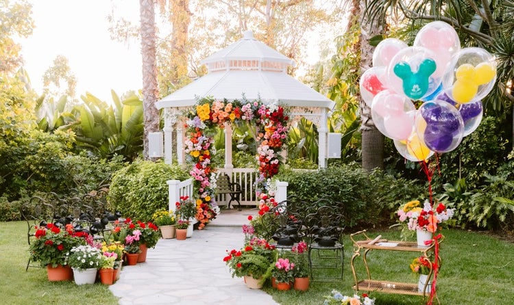 The Adventure Lawn Gazebo with a flower arch and potted plants along the walkway