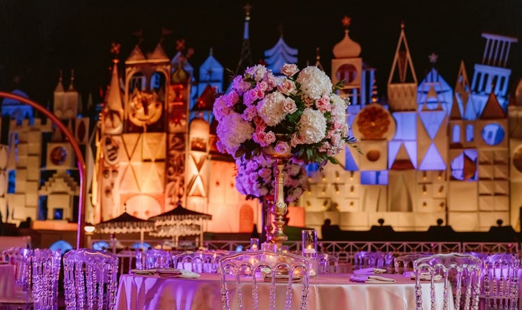 Tables and chairs decorated with flowers and set up in front of ‘it’s a small world’ in Disneyland Park