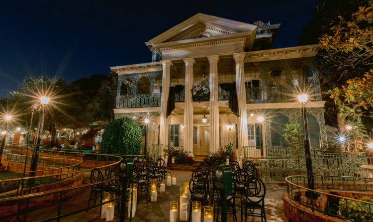 The Haunted Mansion with columns and ornate balconies illuminated for an evening wedding ceremony with candles