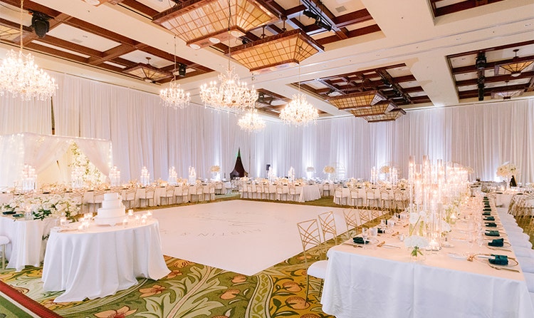 A ballroom with high ceilings and curtains surrounding a dance floor in the center of the room