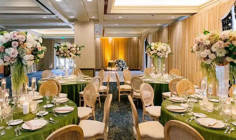 Reception room with dining tables topped with tall floral arrangements