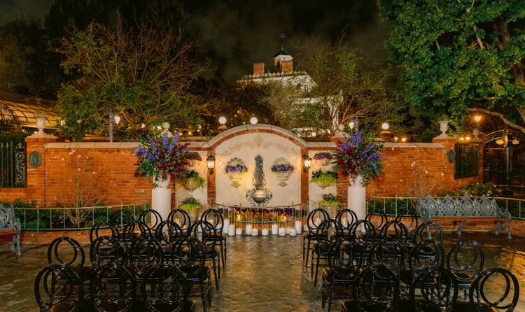 The Magnolia Park Terrace wedding venue with a fountain, floral arrangements, chairs and Haunted Mansion in the background