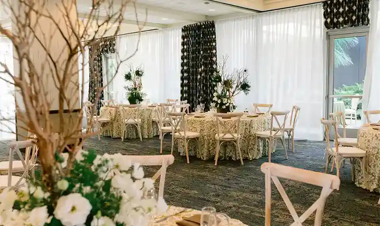 A reception room with dining tables topped with ornate floral centerpieces