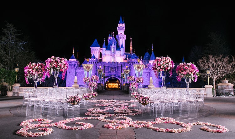Chairs, flowers and an aisle of petals ready for a wedding ceremony in front of Sleeping Beauty Castle