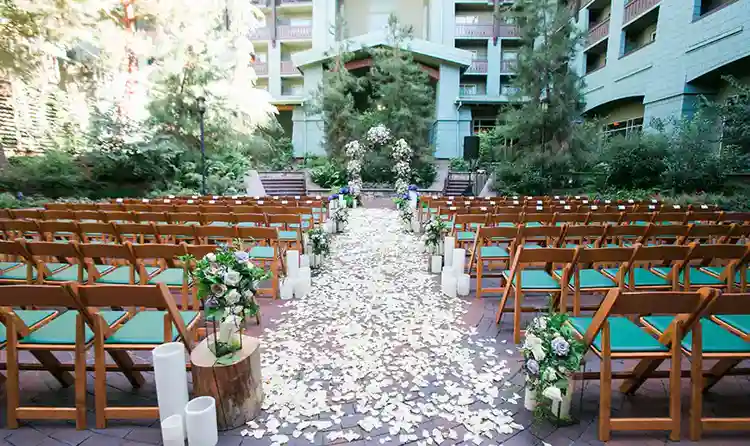 a courtyard with of chairs, flower petals, trees, flowers and floral archway