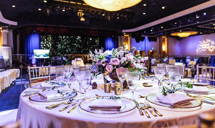A floral centerpiece and several place settings arranged on a round table
