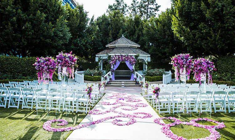 Tall vases of vibrant flowers and several folding chairs in front of a gazebo