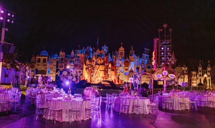 Tables and chairs decorated with flowers and set up in front of ‘it’s a small world’ in Disneyland Park
