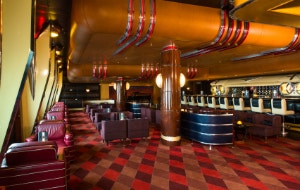 A retro themed lounge with burgundy chairs and a bar replicating the front of a 1950s Cadillac