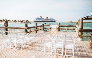 Folding chairs arranged in front of a podium on a deck overlooking the ocean at The Wedding Pointe on Disney Castaway Cay
