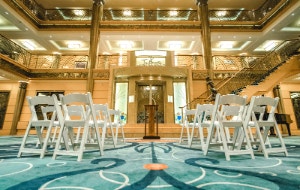 Folding chairs arranged in front of a podium in The Atrium aboard the Disney Wonder