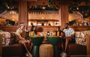 Two couples enjoying drinks together at Skipper Society, a Jungle Cruise themed bar aboard the Disney Treasure