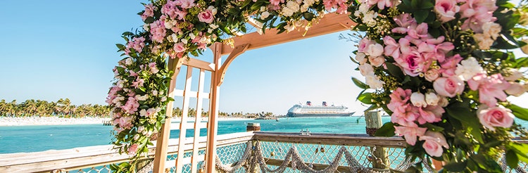 A wedding gazebo with flowers and a Disney cruise ship in the background