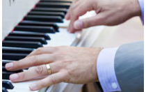A pair of hands are positioned on a piano keyboard, playing a chord