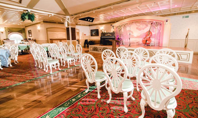 Rows of chairs facing a podium, with tables and chairs set up behind them