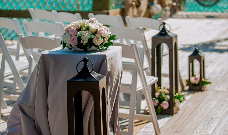 A cloth covered table holding a bouquet of flowers next to a large lantern