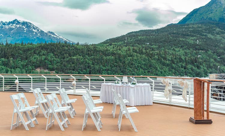4 rows of chairs facing a podium on the patio area of the ship’s deck