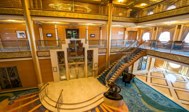 The Atrium in the Disney Dream featuring a staircase, grand piano and statue of Helmsman Mickey Mouse
