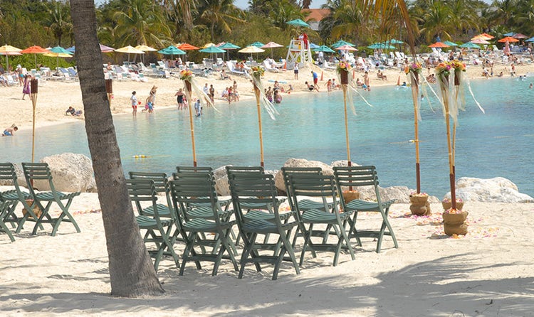 Two rows of chairs on the edge of a beach in front of tiki torches