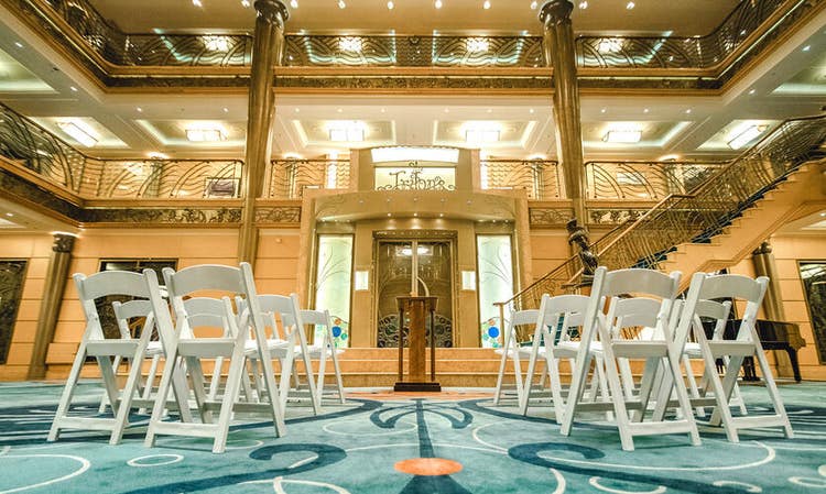 A few rows of chairs facing a wooden podium inside The Atrium