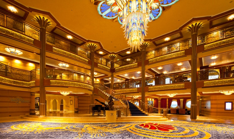 The Atrium in the Disney Dream featuring a staircase, chandelier, grand piano and statue of Captain Donald Duck