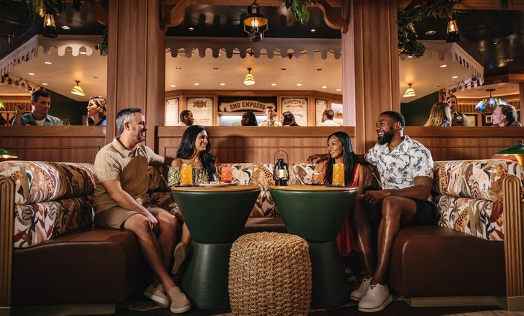 Four friends sitting in a booth at the Skipper Society on the Disney Treasure