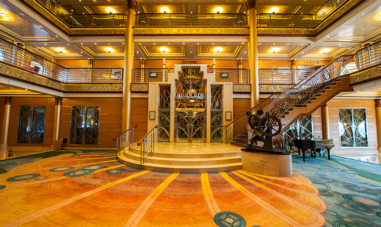 The Atrium on the Disney Dream featuring a staircase, grand piano and statue of Helmsman Mickey Mouse