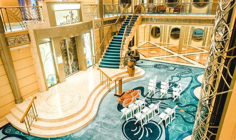 A staircase leading to a platform landing in a spacious room set with chairs and a podium