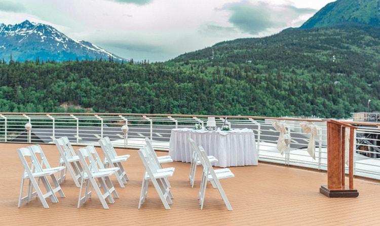 Chairs, a podium and a table with a wedding cake set up for a ceremony at the Deck 10 Aft Overlook on the Disney Magic
