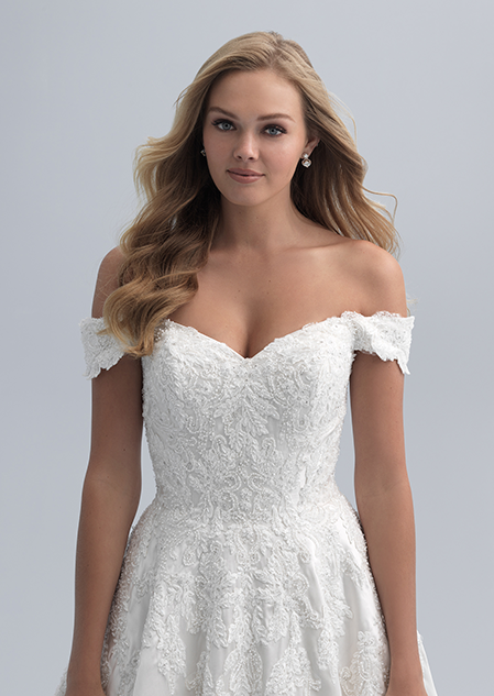 A close up of a woman wearing an off the shoulder wedding dress with a textured bodice