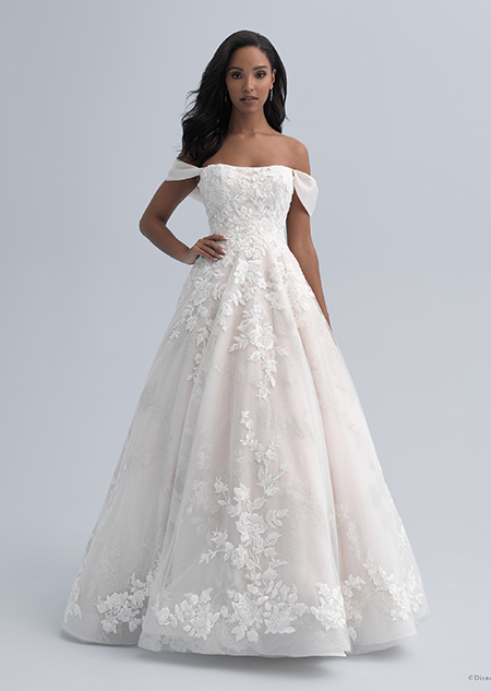 A bride in an off the shoulder dress with straps hanging above her elbows and a full skirt adorned with large flowers