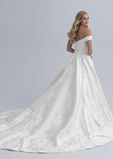 A bride looks over her shoulder while wearing an off the shoulder wedding dress with a long train