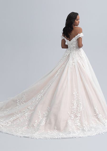 The back view of a woman wearing a dress with an off the shoulder neckline and flowers adorning a full skirt
