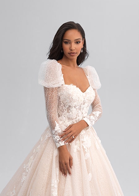 A woman wearing a long sleeved and lacy wedding gown with puffy sleeves
