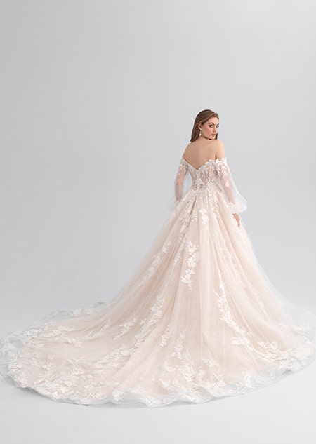 A woman looking over her shoulder wearing a lacy wedding dress with a long train