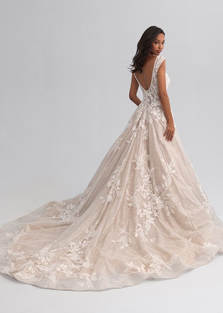 A woman looking over her shoulder wearing a sleeveless wedding gown covered with a shimmery lace