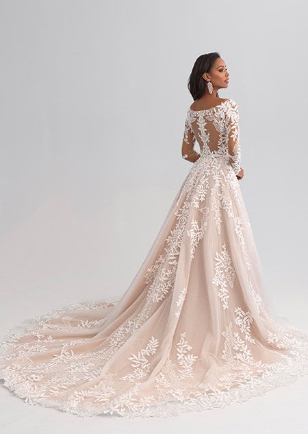 A woman looking over her shoulder wearing a long sleeved and lacy wedding gown covered with lace