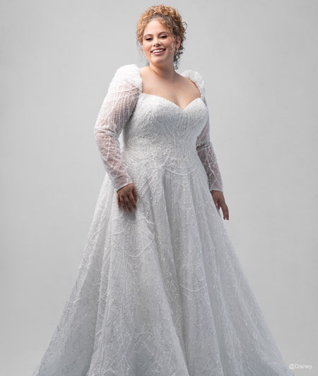 The front of a bride wearing a Cinderella inspired A line gown featuring a V neckline, beading and long, sheer sleeves