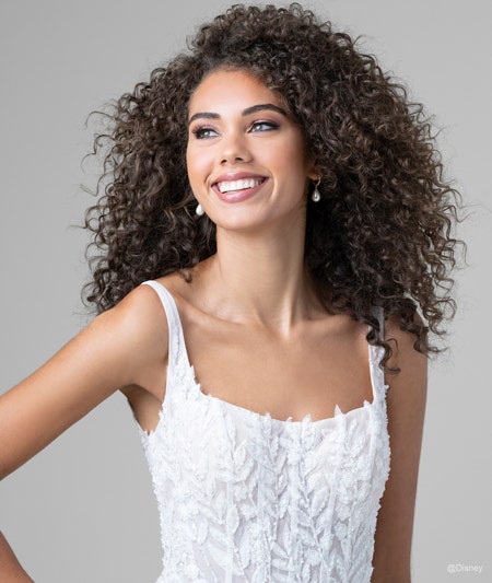 The bodice of a bride wearing a Pocahontas inspired sheath gown featuring a square neckline and leaf detail using lace and sequins