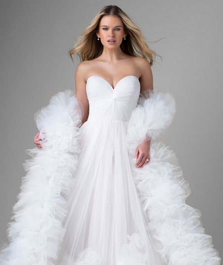 The front of a bride wearing a Rapunzel inspired ball gown featuring a sweetheart neckline, ruffles around the hem and a ruffled boa