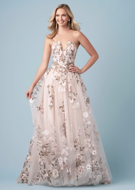 A bride wearing a Pocahontas inspired A line wedding gown featuring a plunging illusion neckline and embroidery of leaves and blossoms