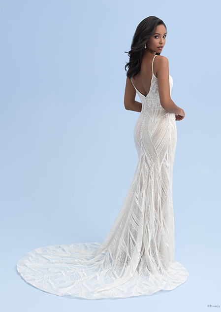 A woman looks over her shoulder while wearing a wedding dress with skinny straps and a small train