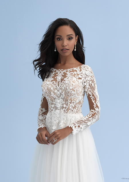 A woman with shoulder length hair wearing a dress with a boat neckline, long sleeves and a large engagement ring