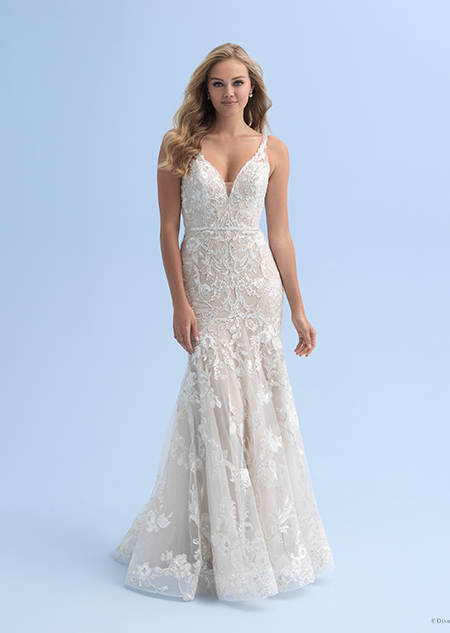 A bride in a form fitting wedding dress with a deep neckline decorated with crystal flowers