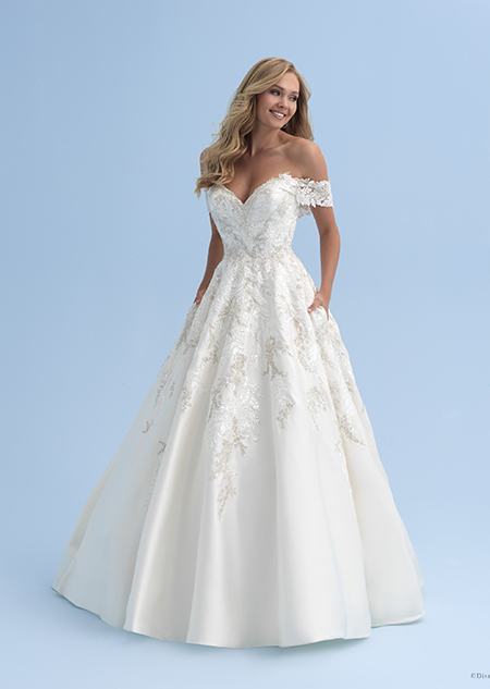 A bride in an off the shoulder wedding dress with straps that cross just above her elbows